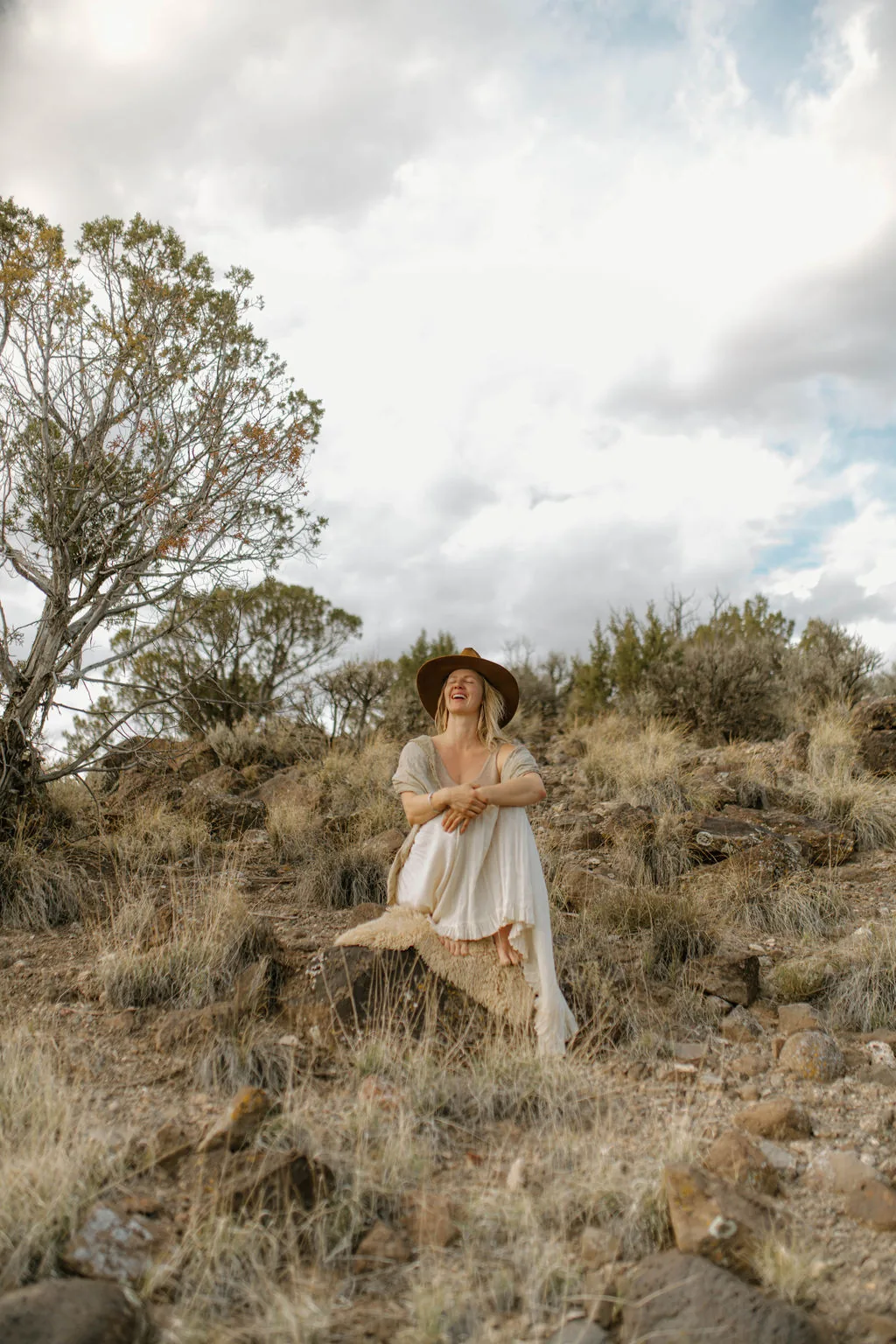 Kate Linehan seated on a rocky hillside under a wide sky