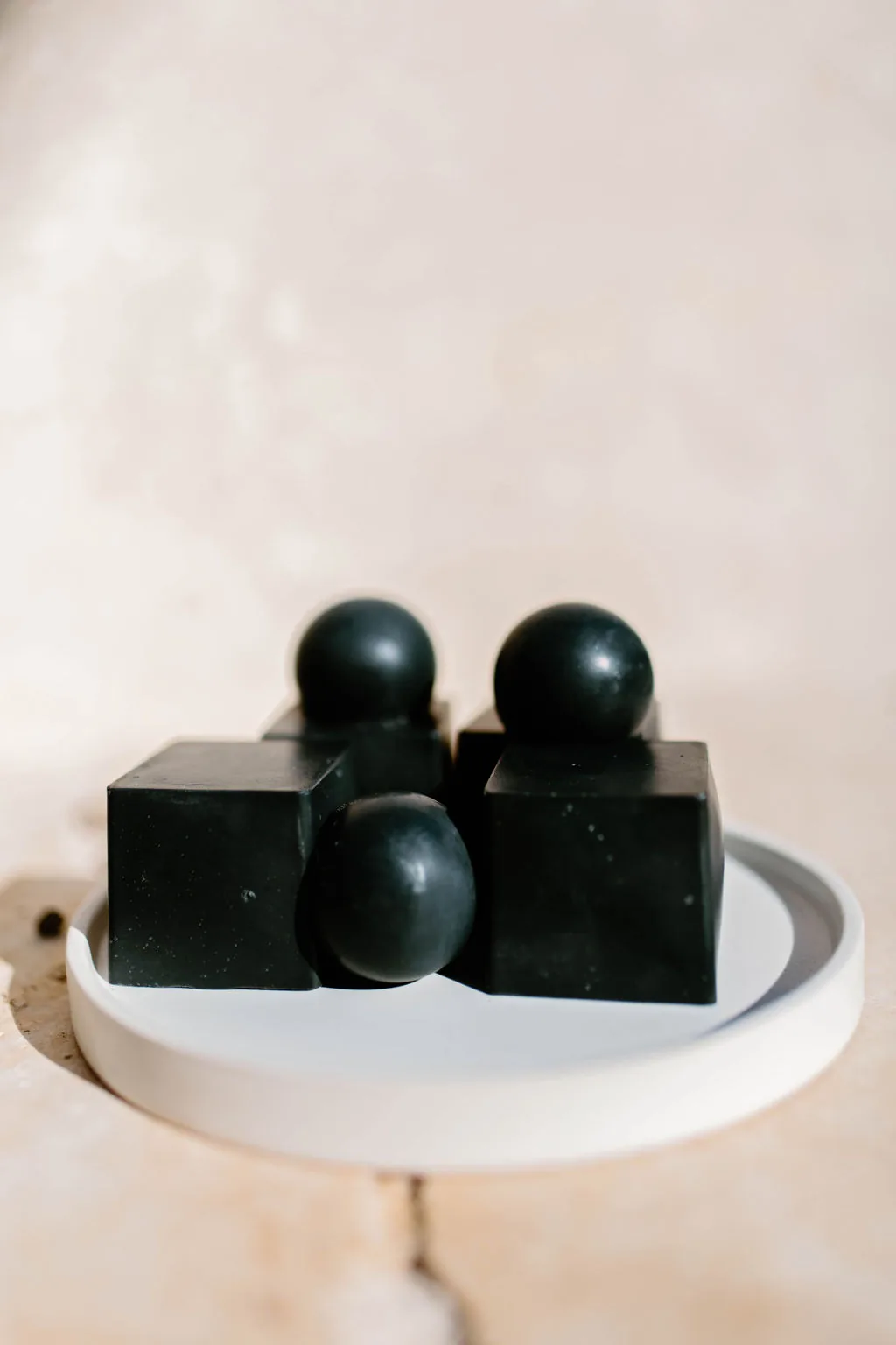 Charcoal soap cast in cubes and spheres on a white tray
